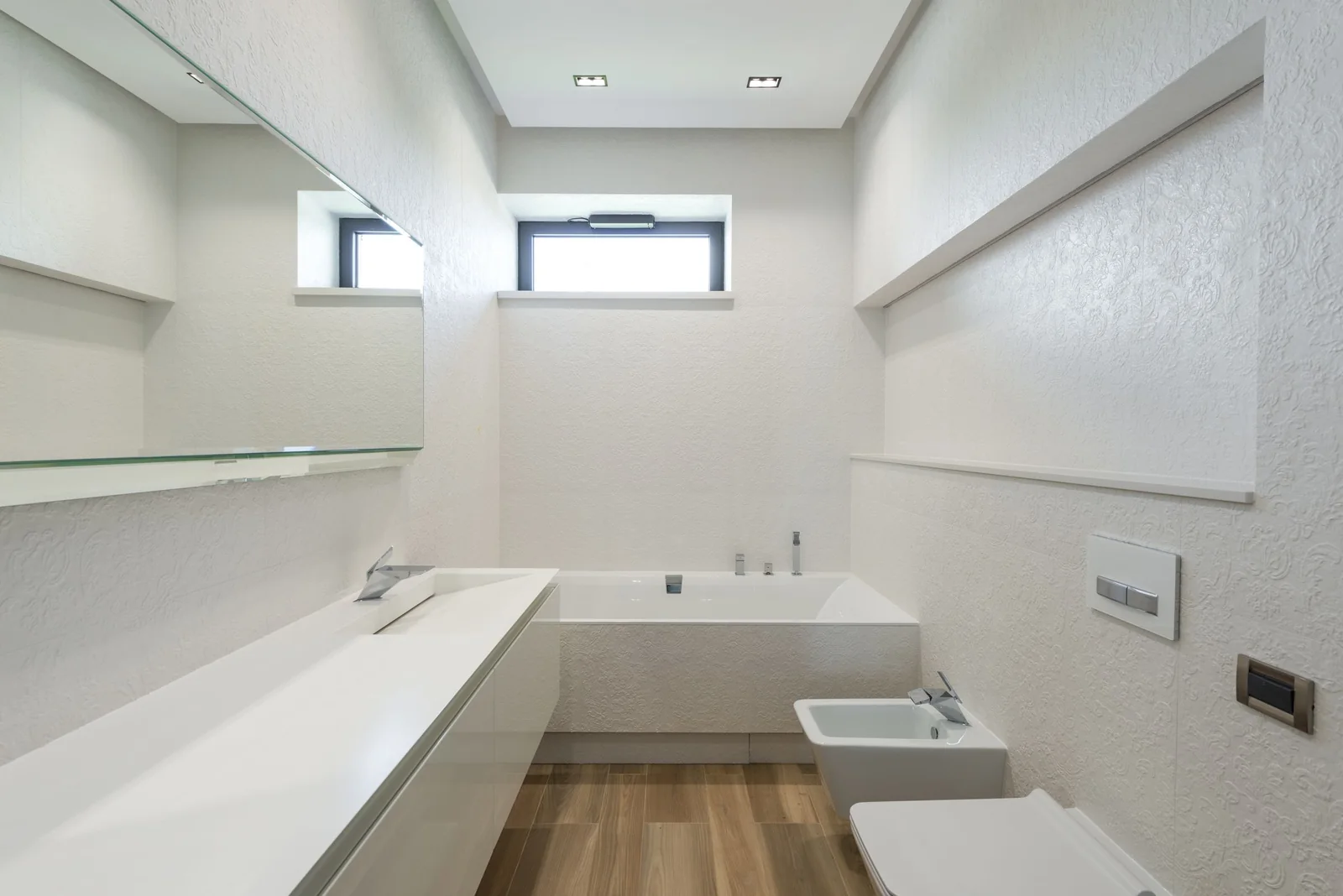 A white bathroom with a small high window