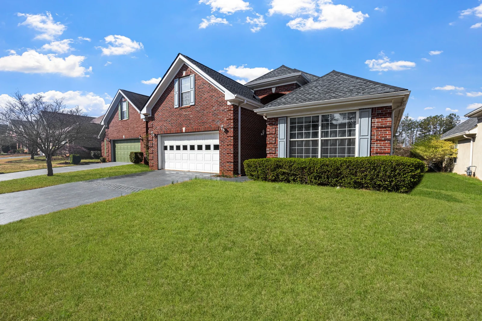 A red brick home with large front windows on a sunny day
