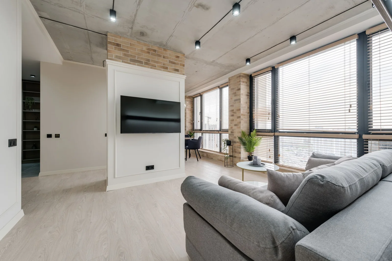 A bright living room with a wall-mounted TV beside large windows