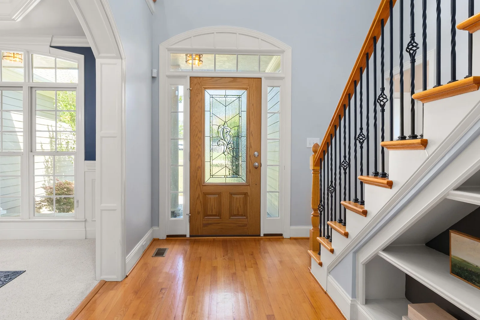 A home’s front door with glass panels and sidelights, seen from the hallway