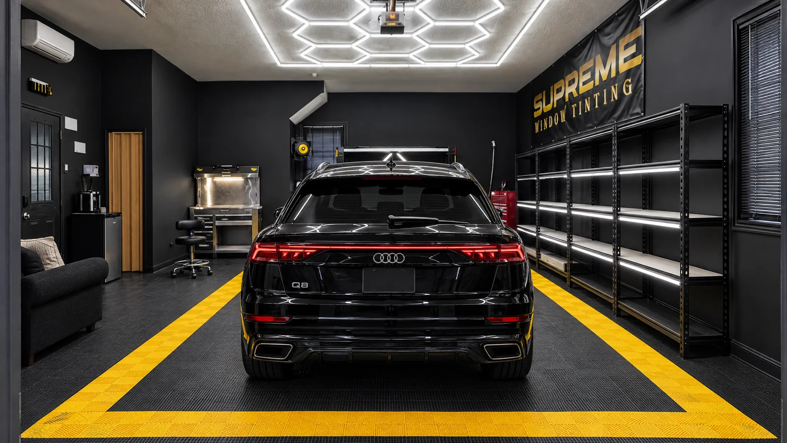A black Audi Q8 in the Supreme Window Tinting studio, the honeycomb lights reflected in its paint