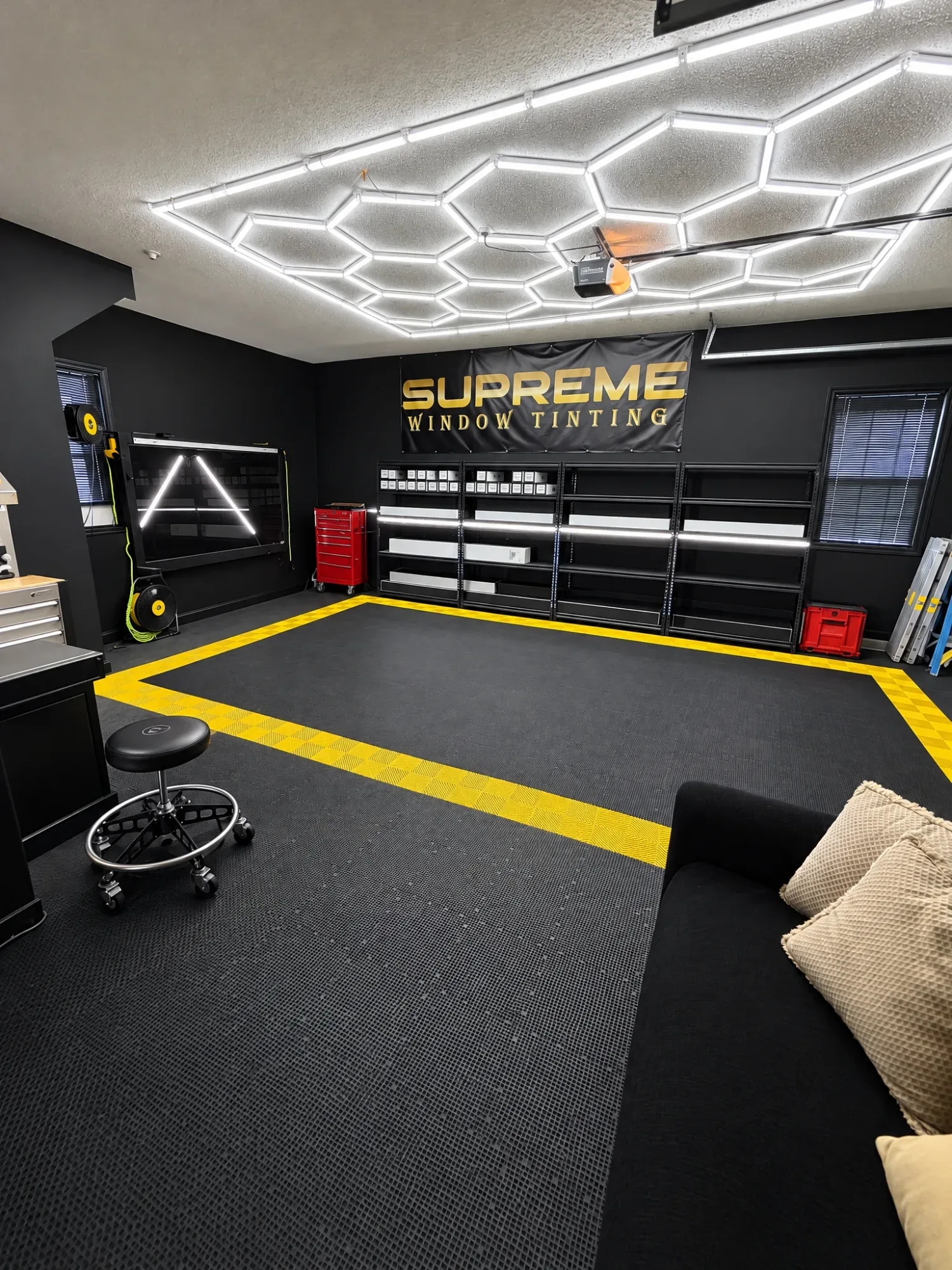 The Supreme Window Tinting studio in Madison: black walls, a yellow-bordered floor and the black and gold Supreme banner
